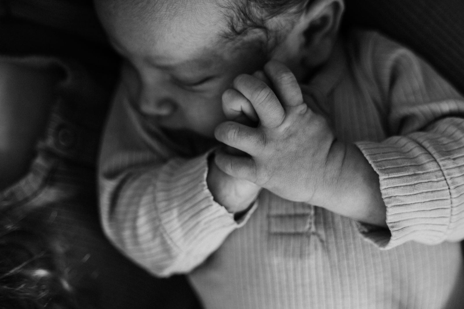 Black and white photo of a parent cradling a newborn's tiny hands