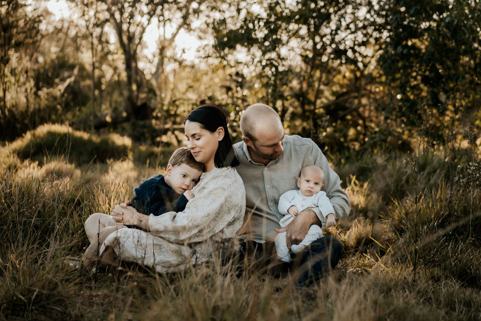 Family snuggled together in long golden grass