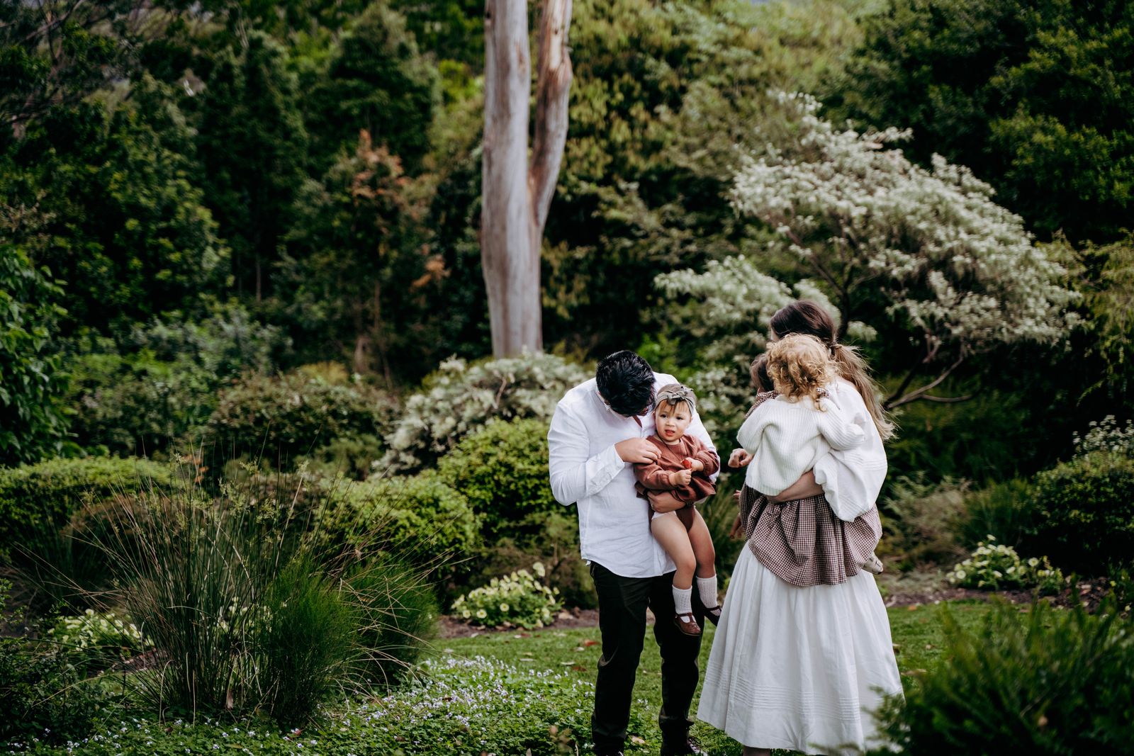 Young family standing in a lush green garden