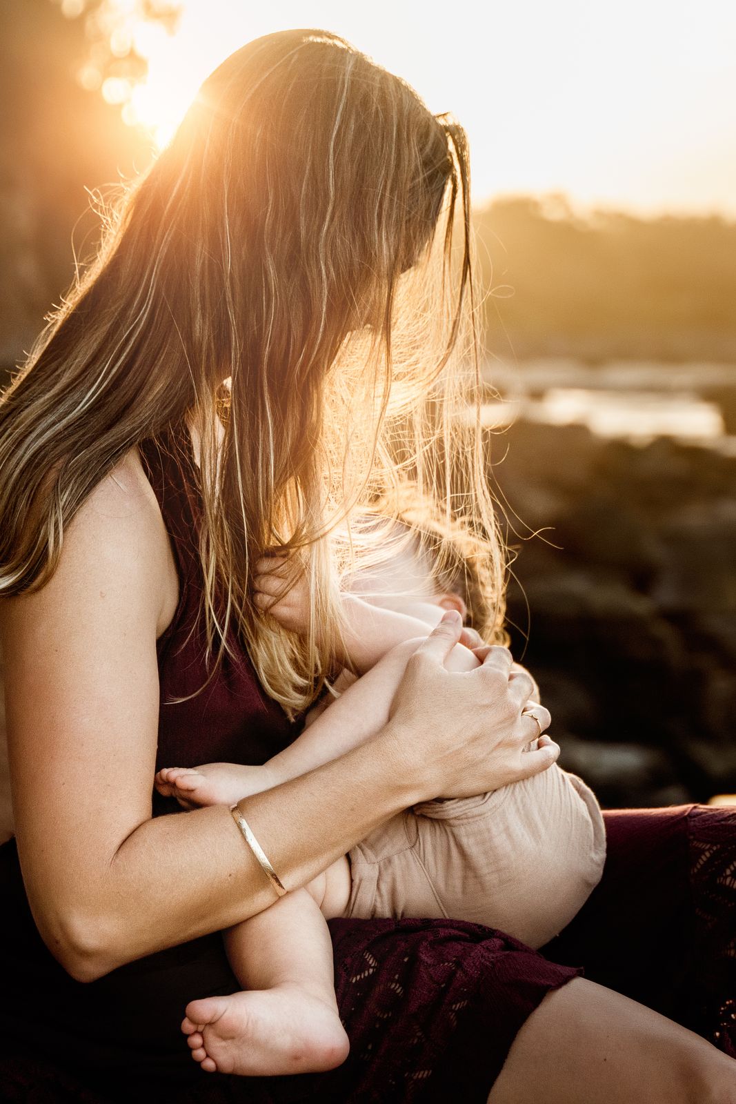 Mum holding her baby close in warm golden backlight
