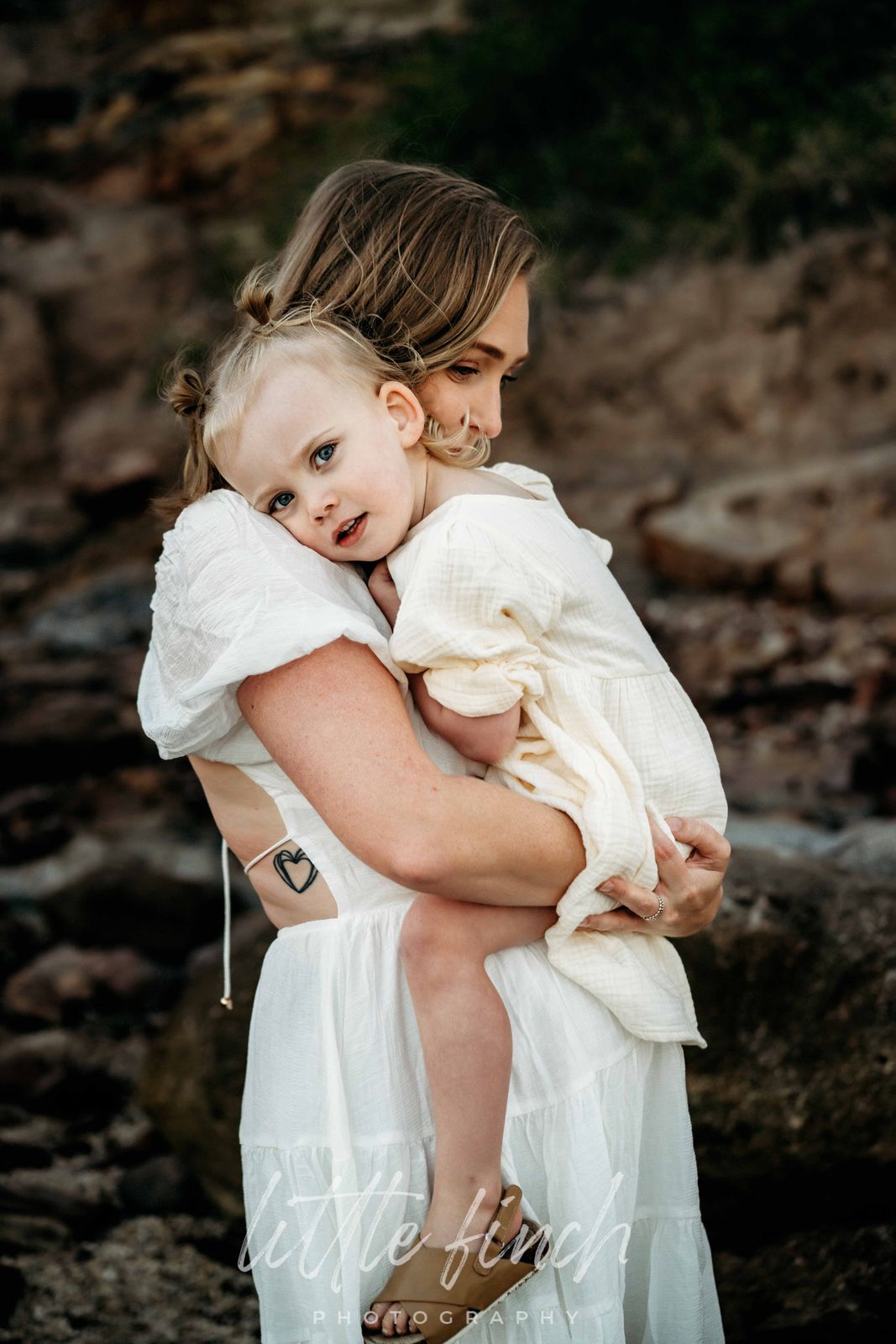 Mum in white holding her toddler close
